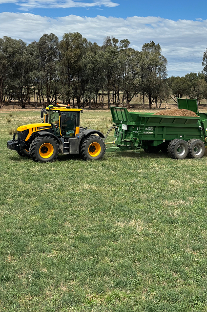 A tractor pulls a trailer loaded with fertilizer.