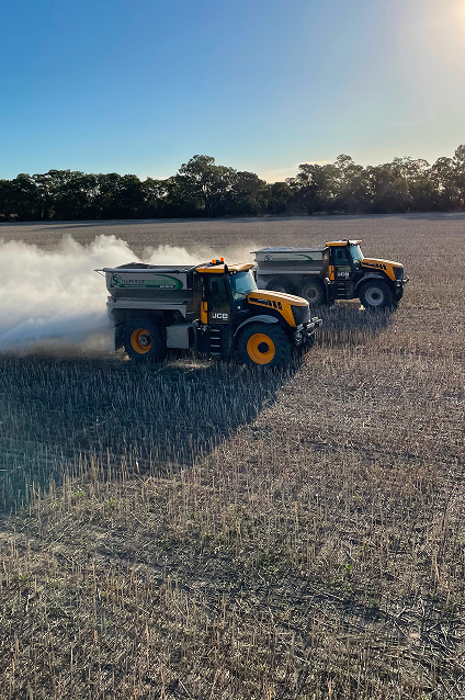 Two tractors spraying a field with smoke, applying granulated fertiliser and lime for precise agricultural management.
