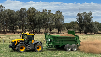 A tractor pulls a trailer loaded with fertilizer.